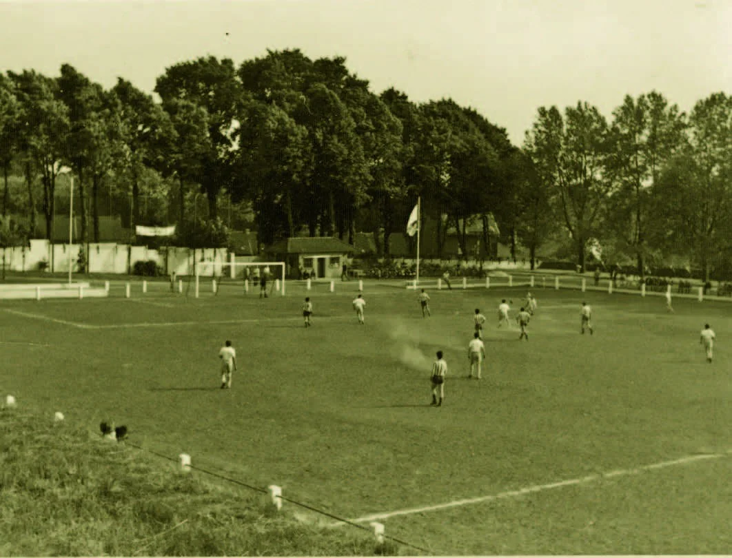 Spielszene auf dem Sandberg 1962 mit Zuschauern am baumbestandenen Hang.