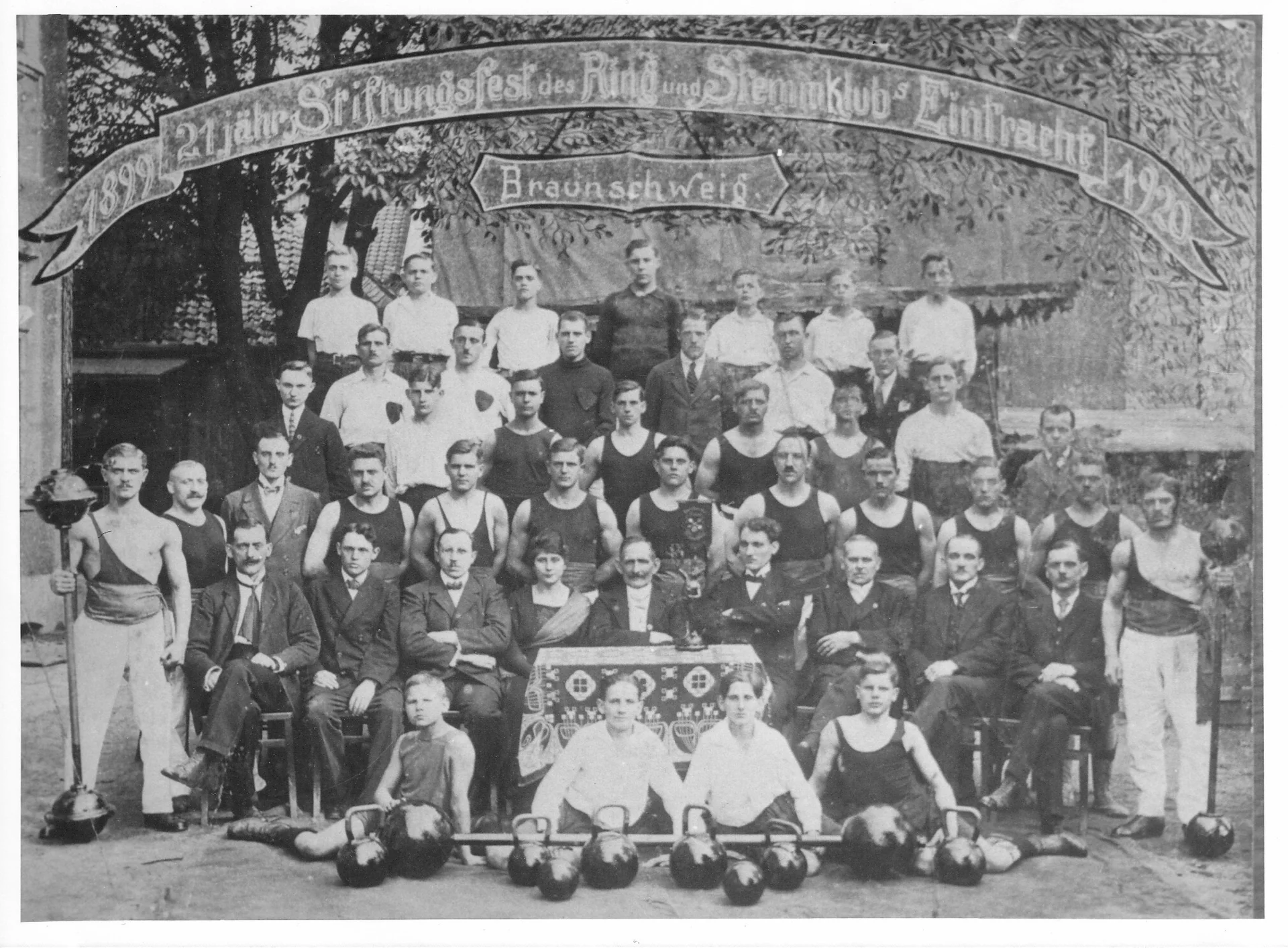 Abbildung 1: Gruppenaufnahme zum 21-jährigen Stiftungsfest des Ring- und Stemmklub „Eintracht“ Braunschweig im Jahr 1920. Auf dem Festbogen sind die Jahreszahlen 1899 und 1920 zu erkennen [1, unpag. Titelseite]