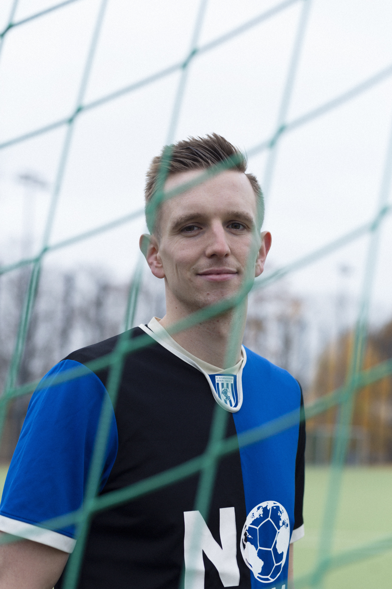 Foto von Anton in einem blau-schwarzen Inter-Trikot, der in die Kamera schaut, die durch ein Tornetz unterbrochen wird.