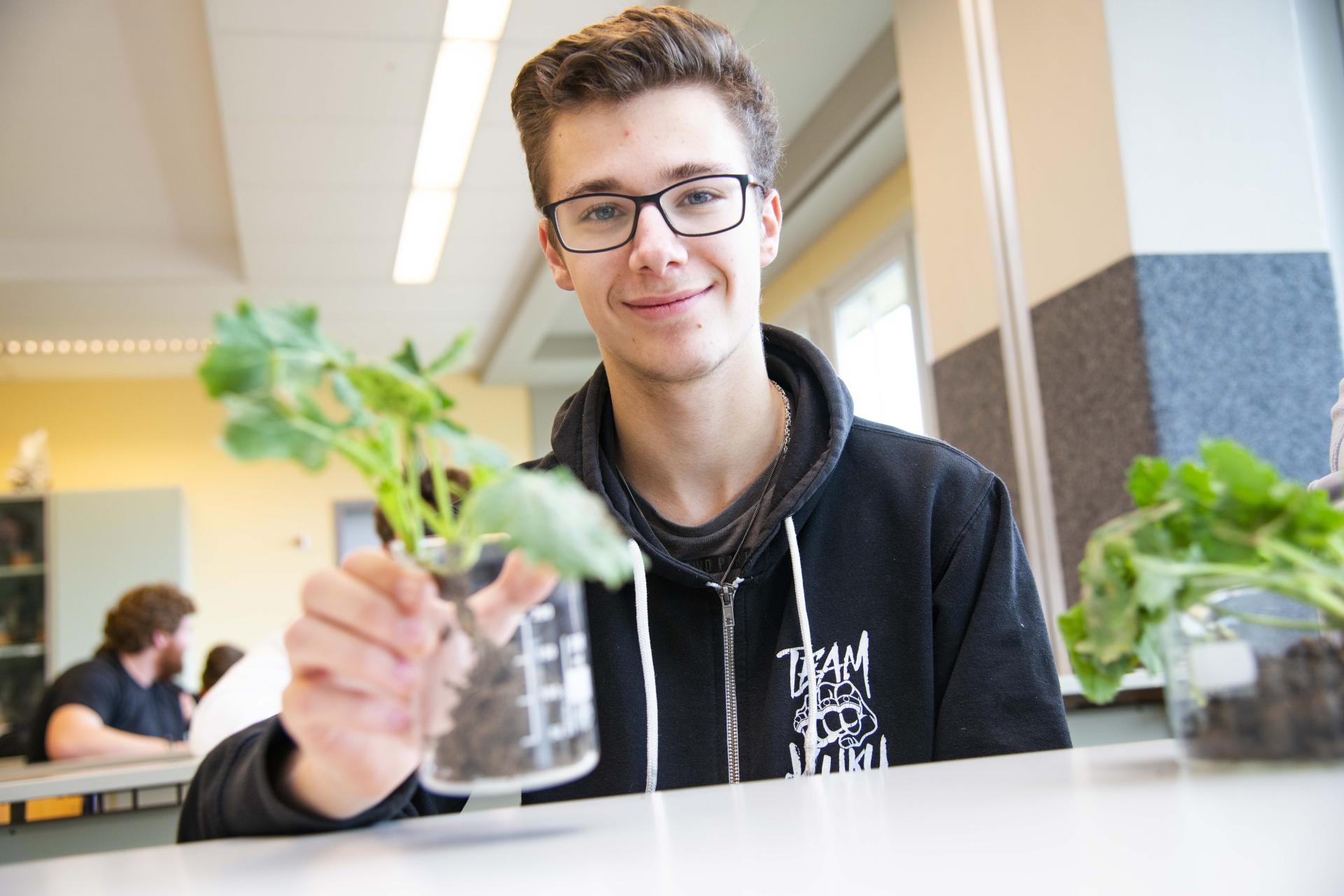 Schüler mit Reagenzglas und Pflanze