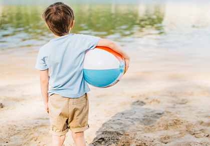 kind-mit-wasserball-am-strand