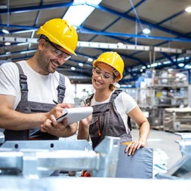 ein-bauarbeiter-und-eine-bauarbeoterin-stehen-in-einer-industriehalle