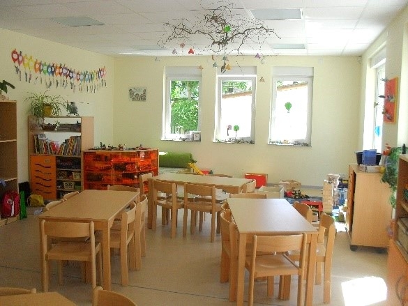 Gruppenzimmer in hellgrün mit Tischen und Stühlen geschmückt