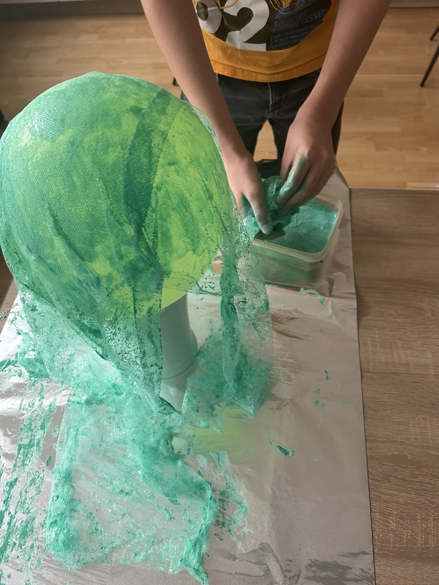 Kind drapiert Tüll auf Luftballon und taucht ein weiteres Stück schon in Farbe