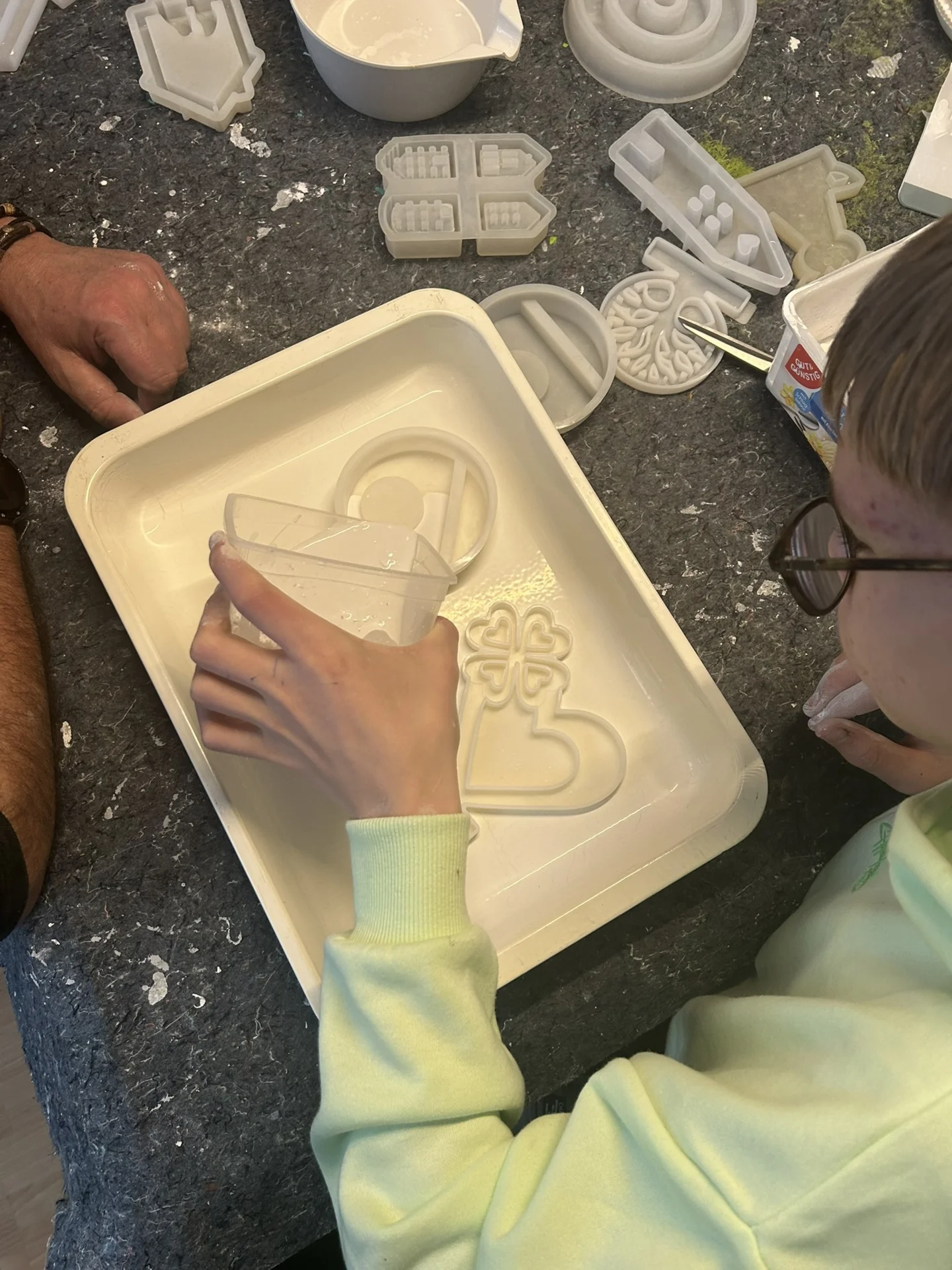 Kind gießt Gips in ein Förmchen